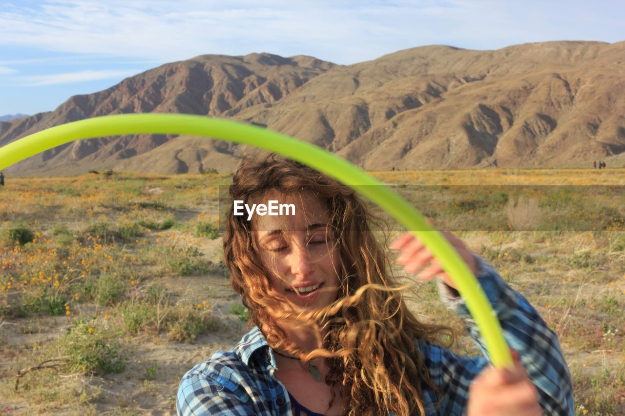 Woman holding plastic hoop against mountains and sky