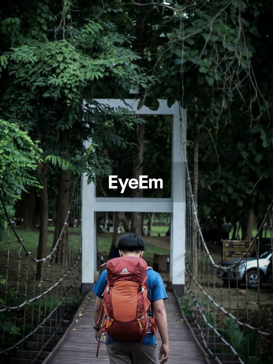 REAR VIEW OF MAN AND WOMAN WALKING ON FOOTBRIDGE