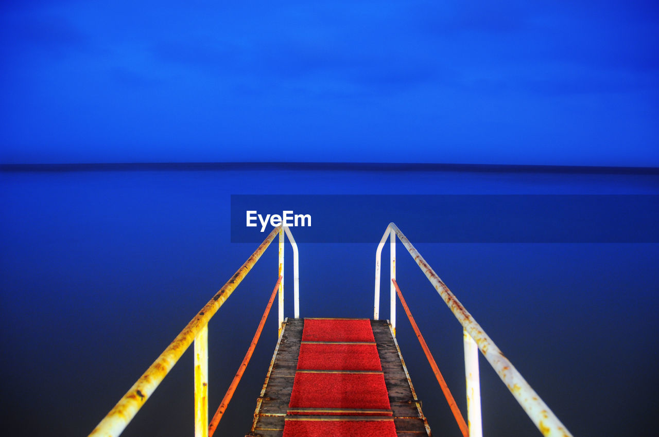 Close-up of railing by sea against clear blue sky