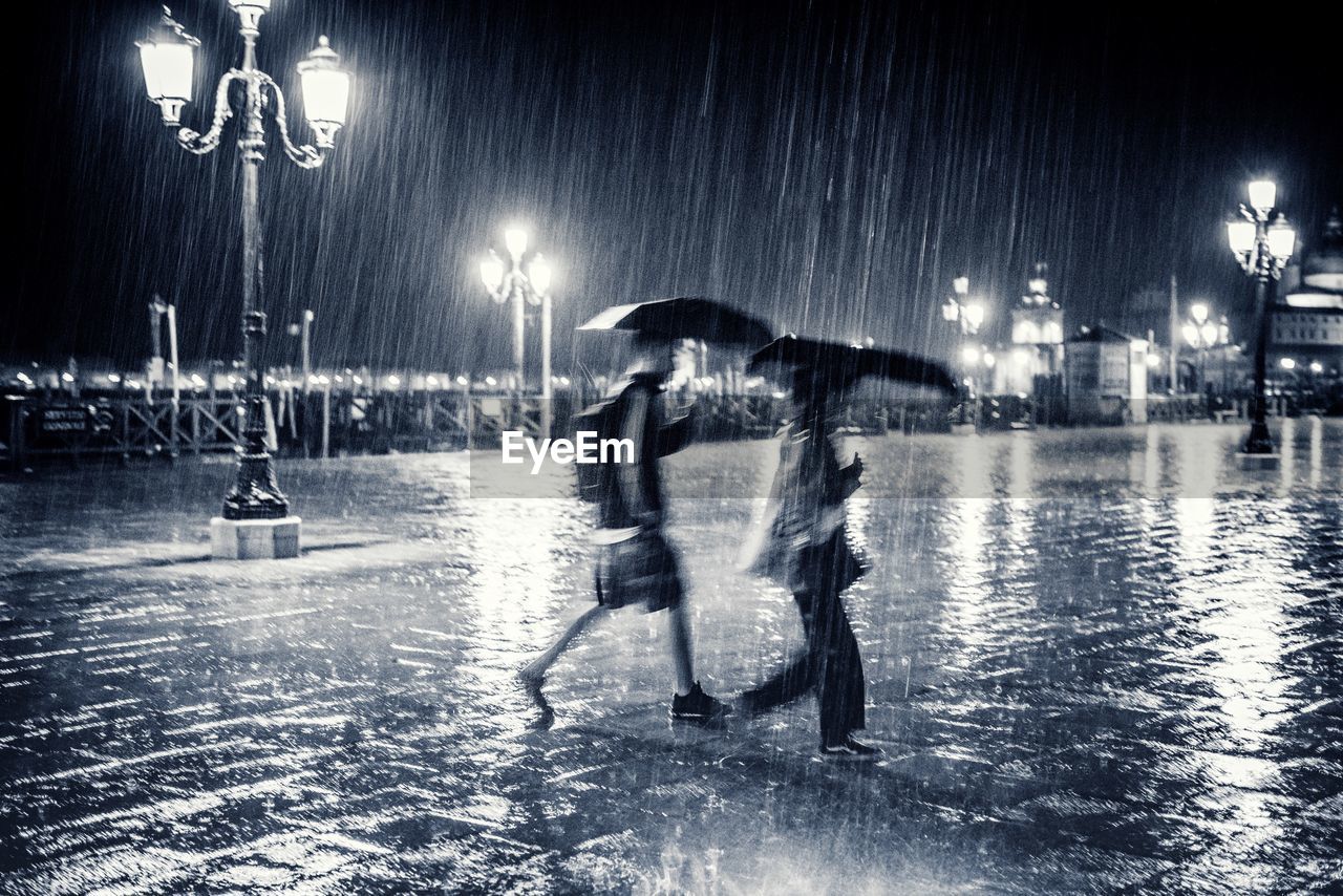 PEOPLE WALKING ON WET STREET AT NIGHT DURING WINTER