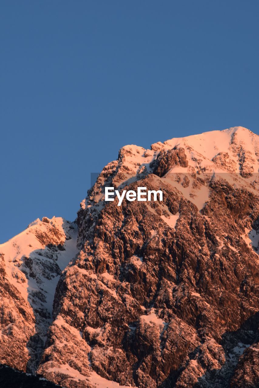 Scenic view of snowcapped mountains against clear blue sky