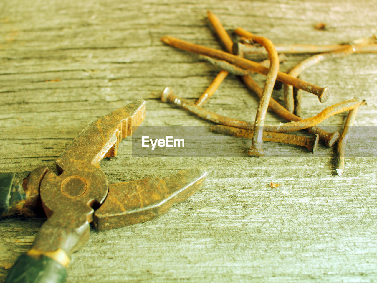 Close-up of old rusty pliers and nails on wooden table