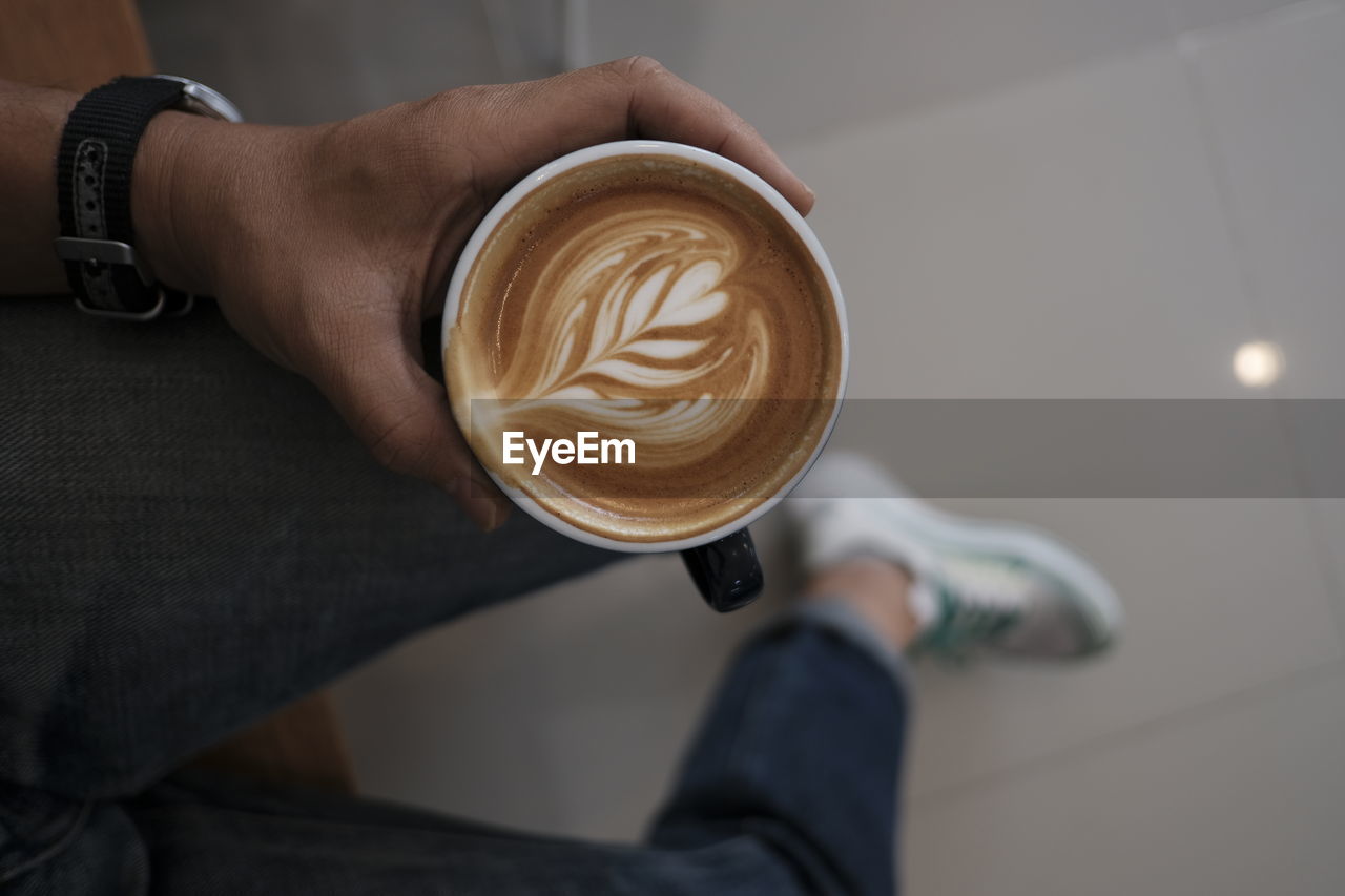 Midsection of woman holding coffee cup on table