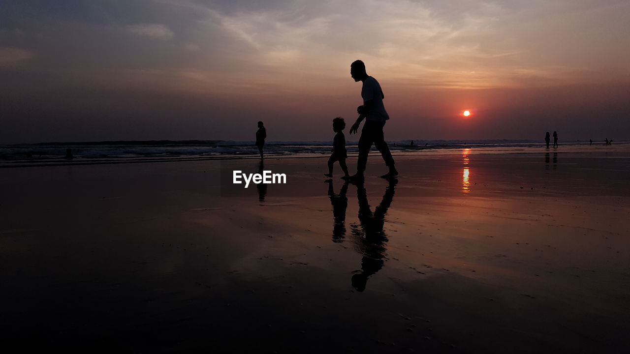 Silhouette of people on beach at sunset