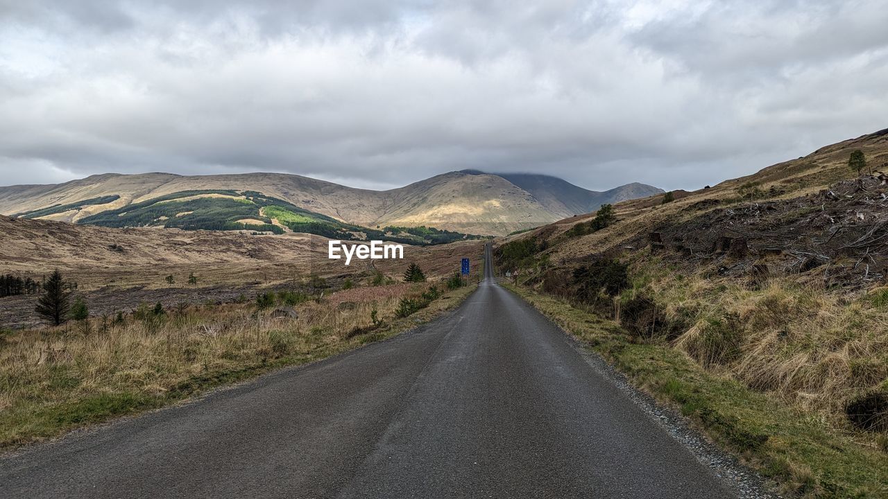 Road amidst field against sky