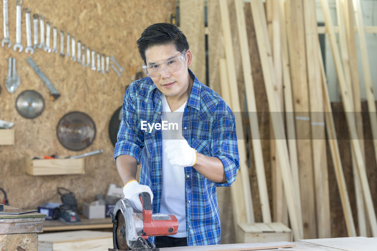 MAN WORKING ON WOOD WITH CAMERA