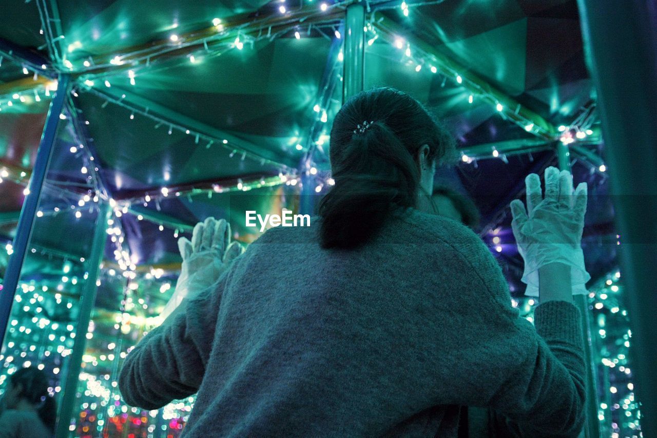 Rear view of woman standing at amusement park in night
