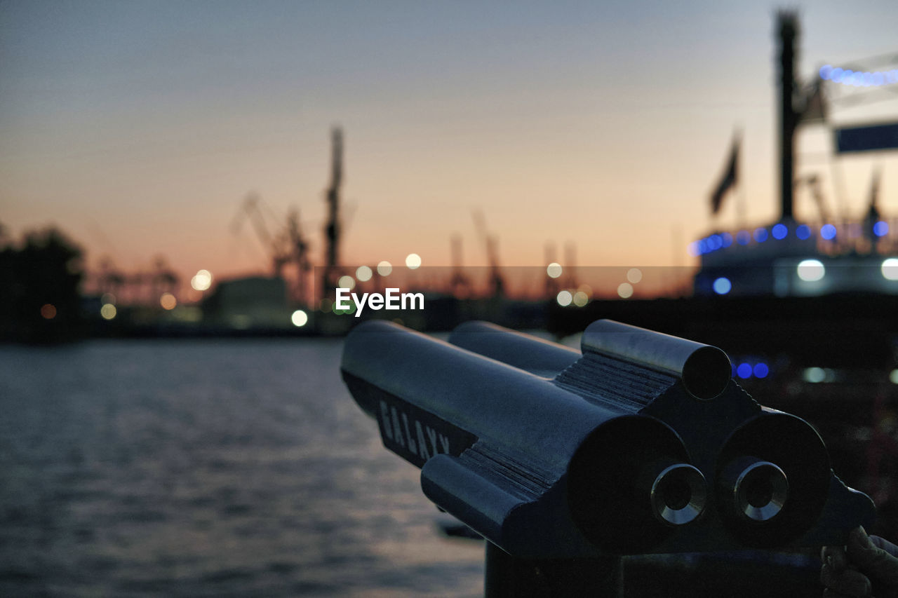 CLOSE-UP OF ILLUMINATED LIGHTING EQUIPMENT ON SEA AGAINST SKY