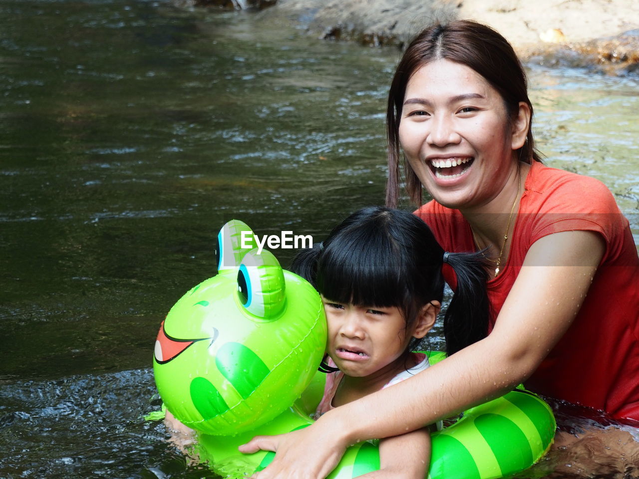 Portrait of happy mother with daughter swimming in river