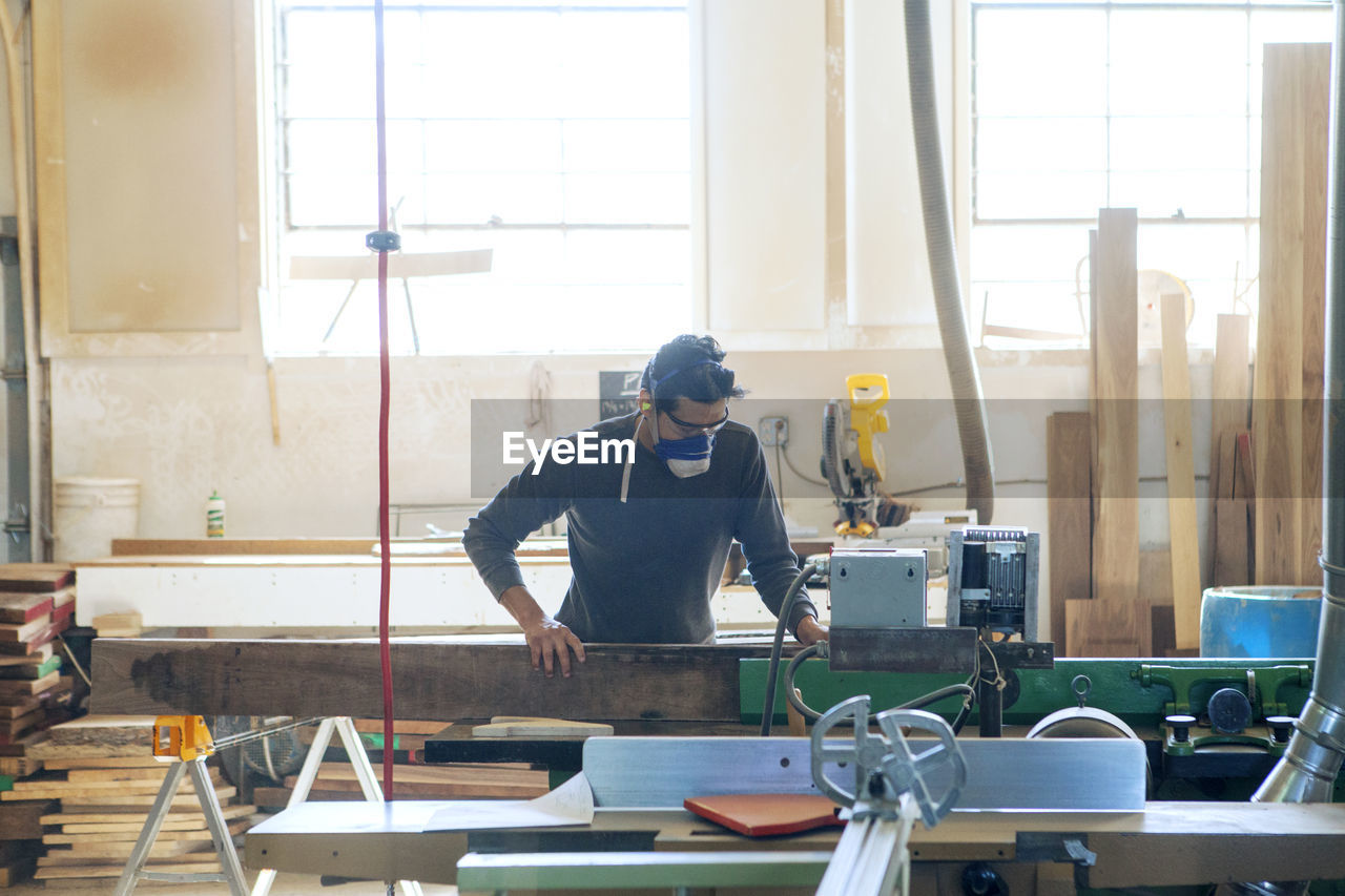 Male carpenter cutting wood in workshop