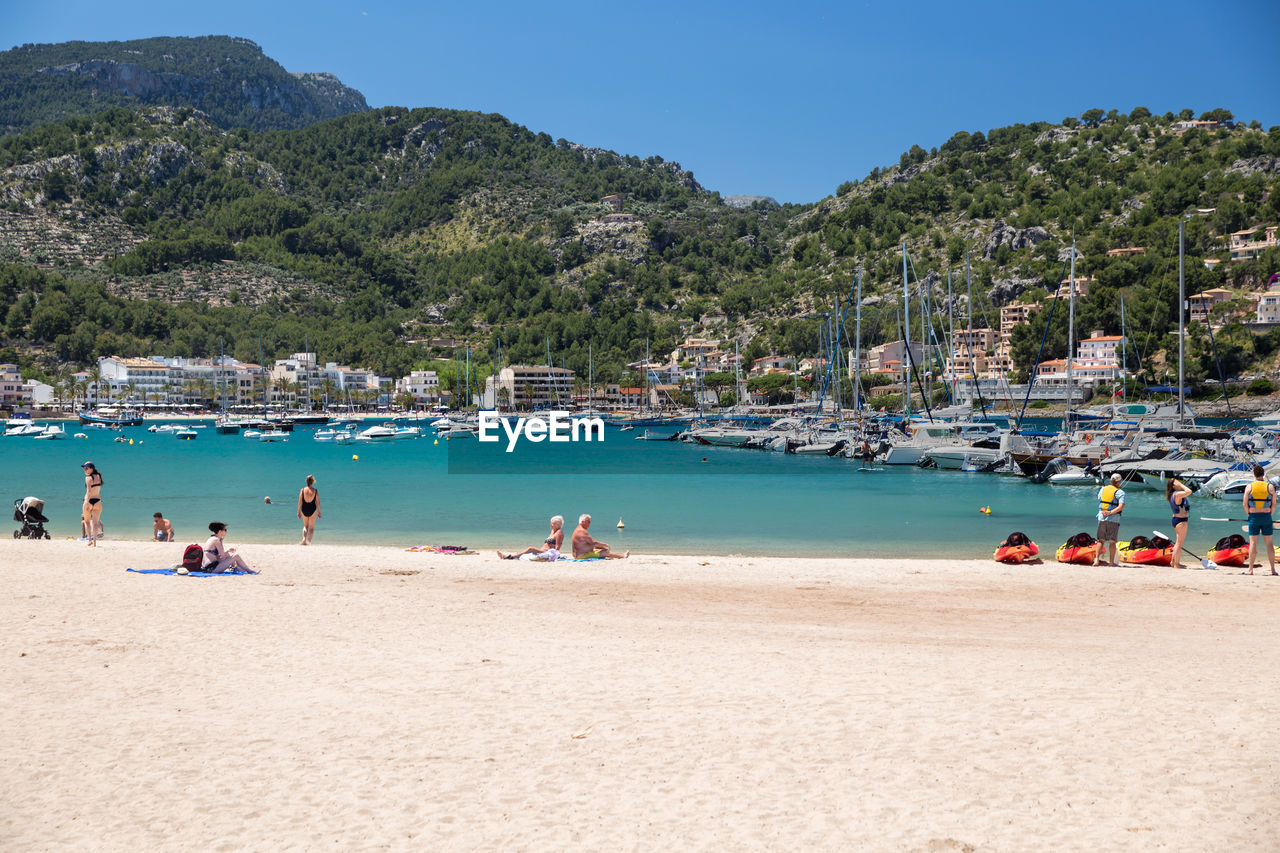 PEOPLE ON BEACH AGAINST MOUNTAIN