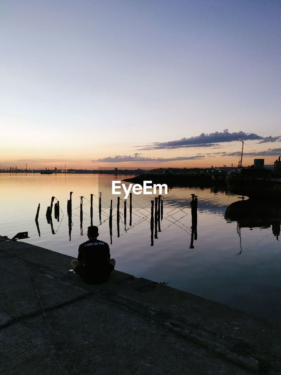 SILHOUETTE OF WOODEN POST IN LAKE AGAINST SKY DURING SUNSET