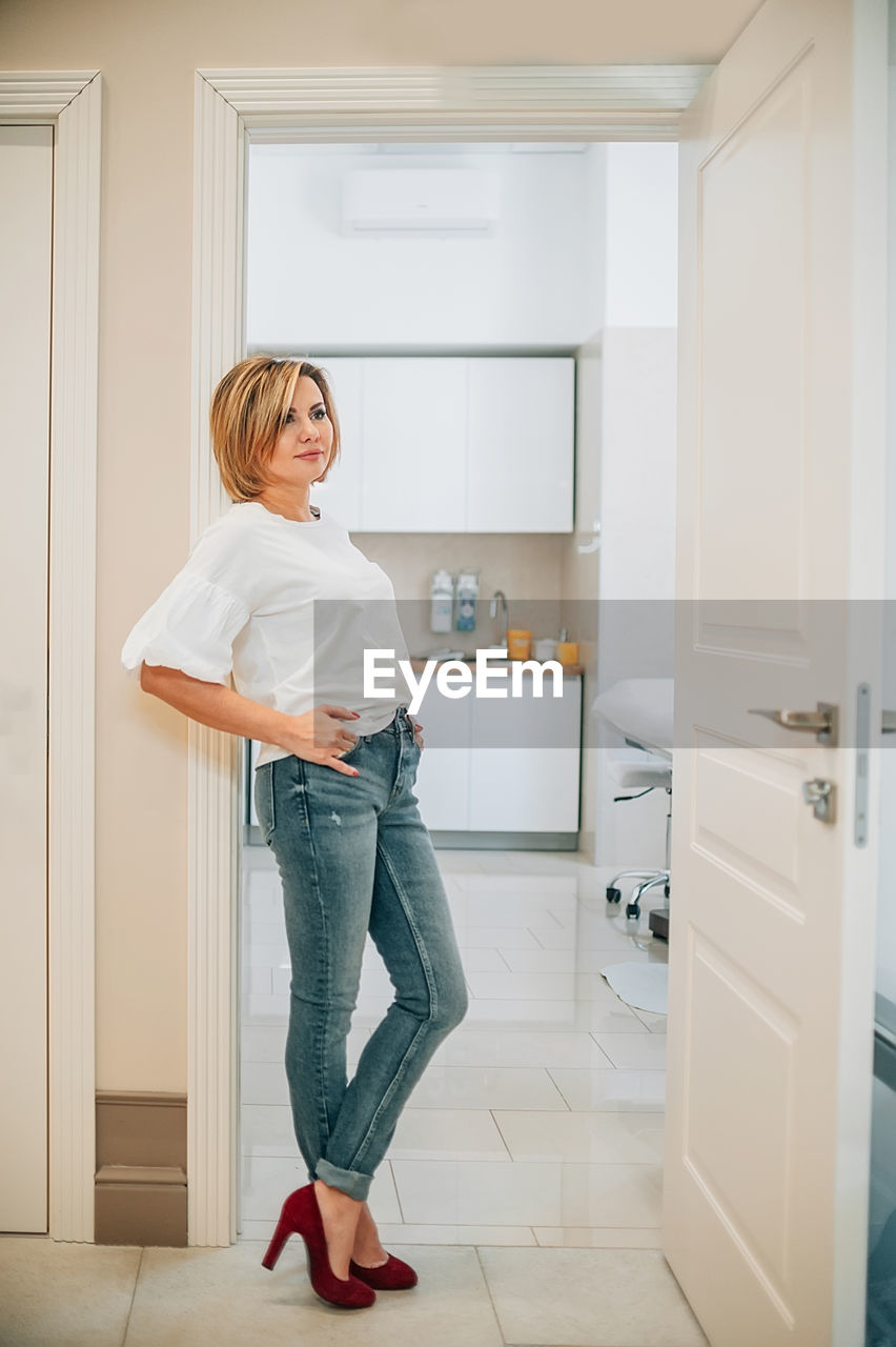 Full length of young woman standing against wall