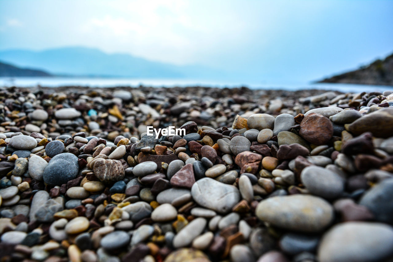 Close-up of pebbles on beach against sky