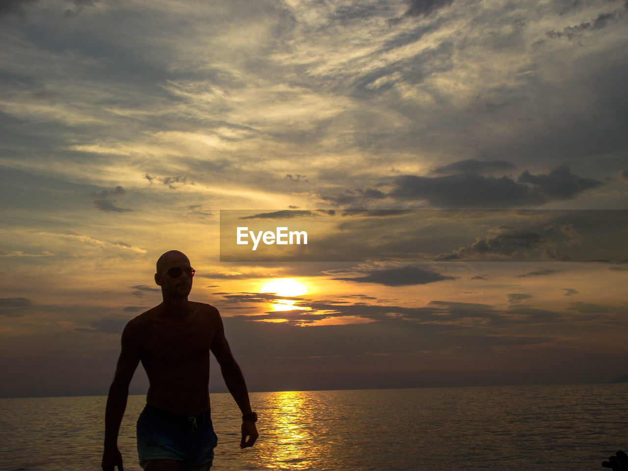 Man at beach against sky during sunset