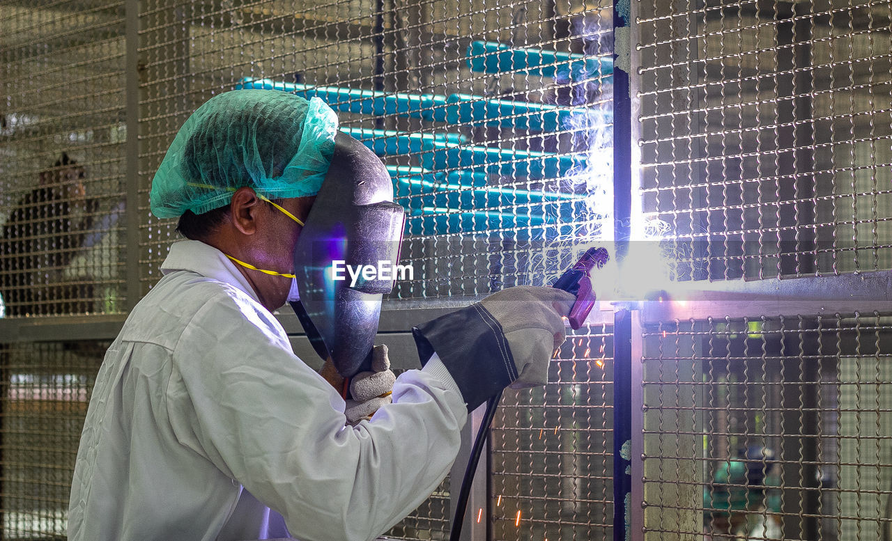 MAN WORKING ON METAL GRATE IN ILLUMINATED OFFICE