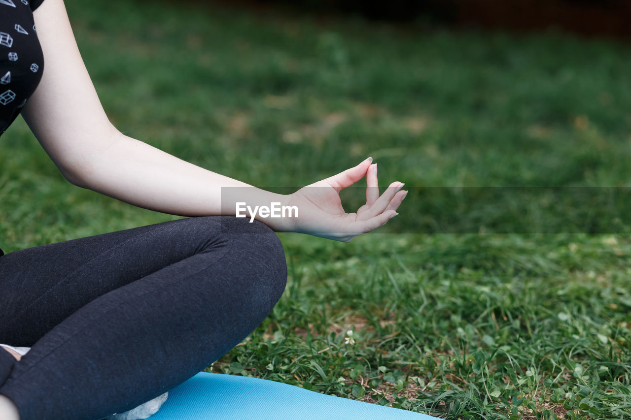 The relaxed girl is doing yoga in the park on carpet