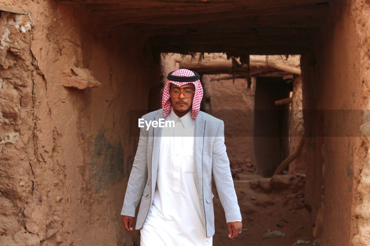 Man wearing traditional clothing walking amidst old ruin