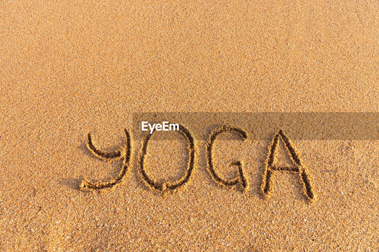 The inscription yoga on the sea sand. sea coast with yoga post with place for text