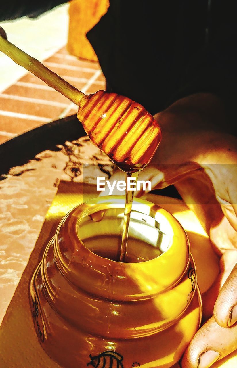 Cropped image of hand holding honey in jar