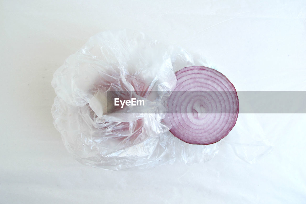 Close-up of onion with plastic on white background