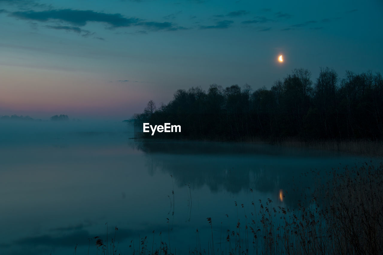 Scenic view of lake against sky at night