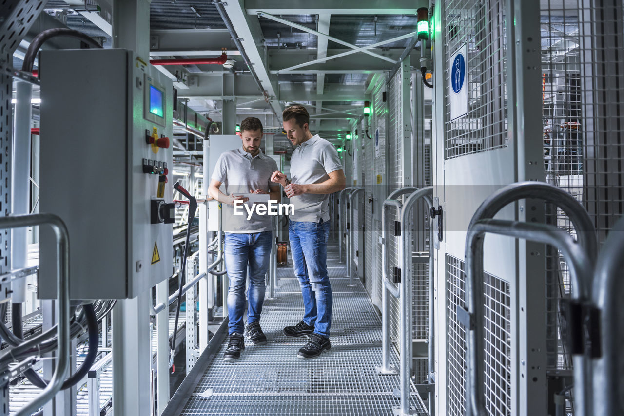 Two men in automatized high rack warehouse looking at tablet