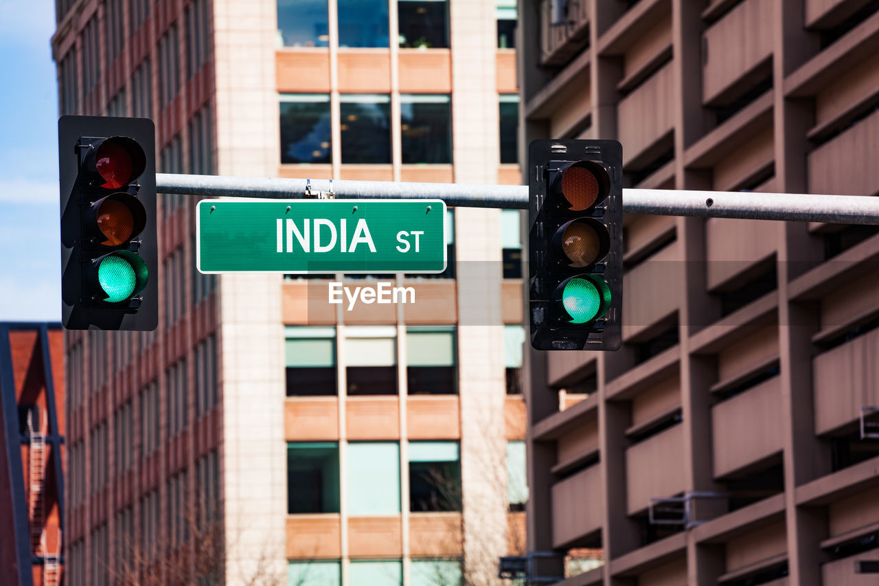 LOW ANGLE VIEW OF ROAD SIGNAL AGAINST BUILDINGS