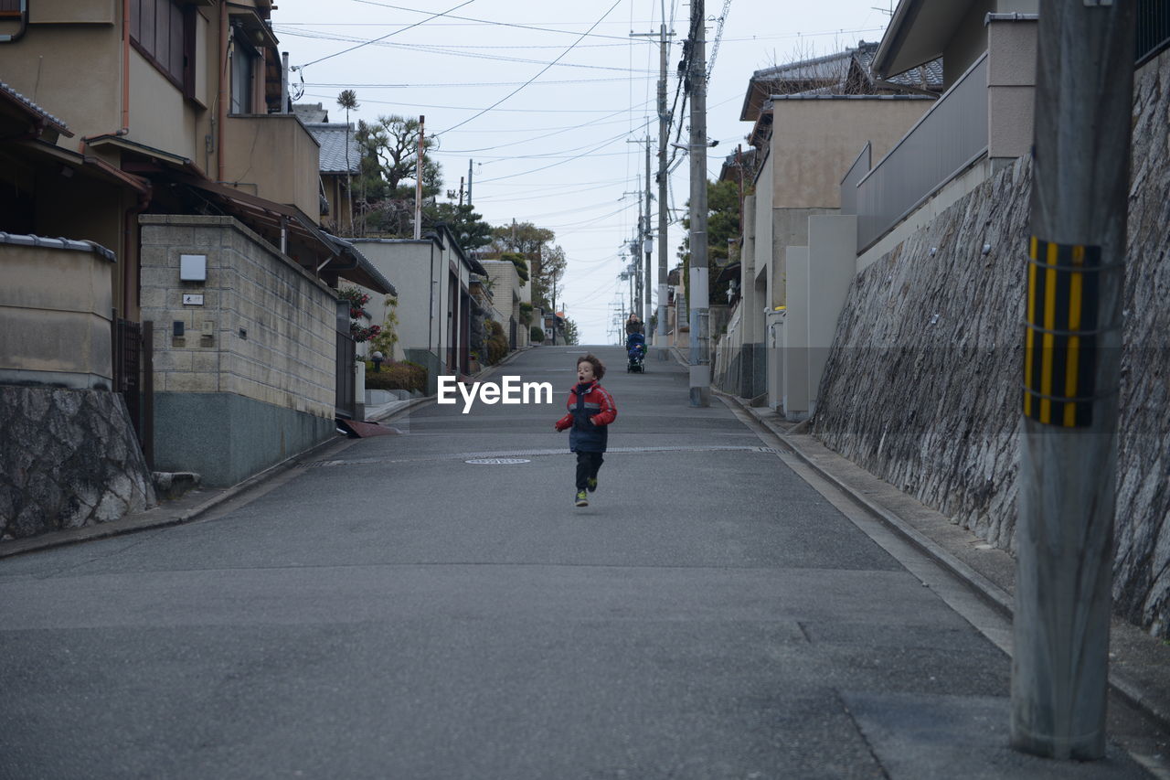 Rear view of man walking on street amidst buildings