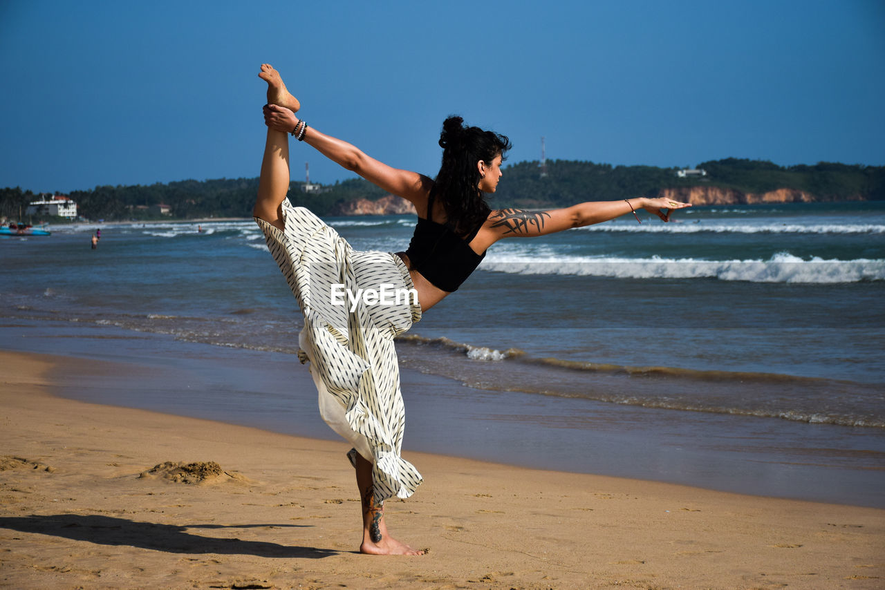 FULL LENGTH PORTRAIT OF YOUNG WOMAN ON BEACH