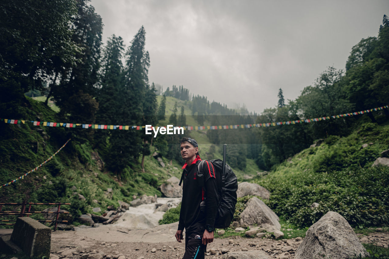 Rear view of man walking on mountain against sky