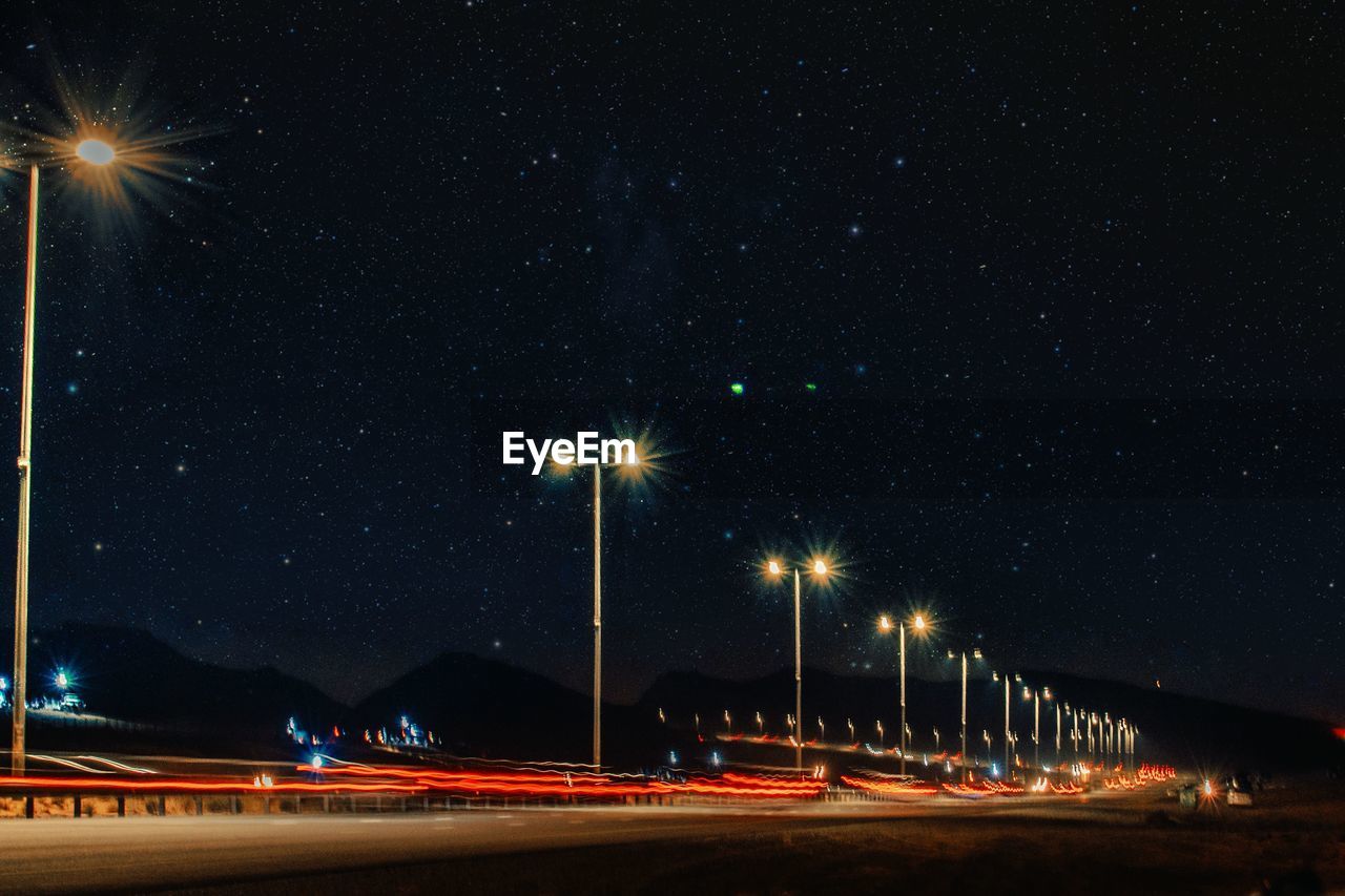 Light trails on street against sky at night