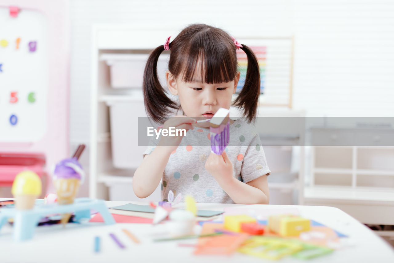 Young girl decorating hand made craft for homeschooling