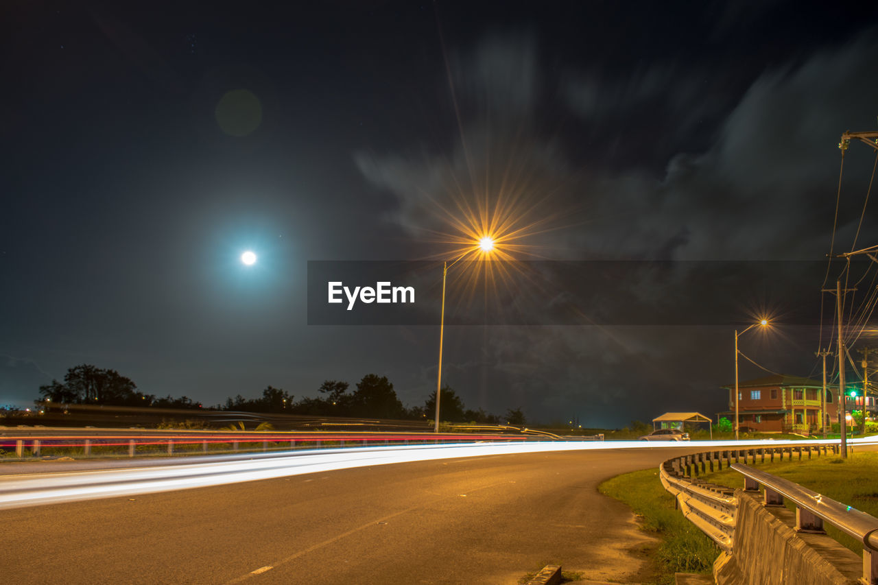 Light trails on road against sky at night