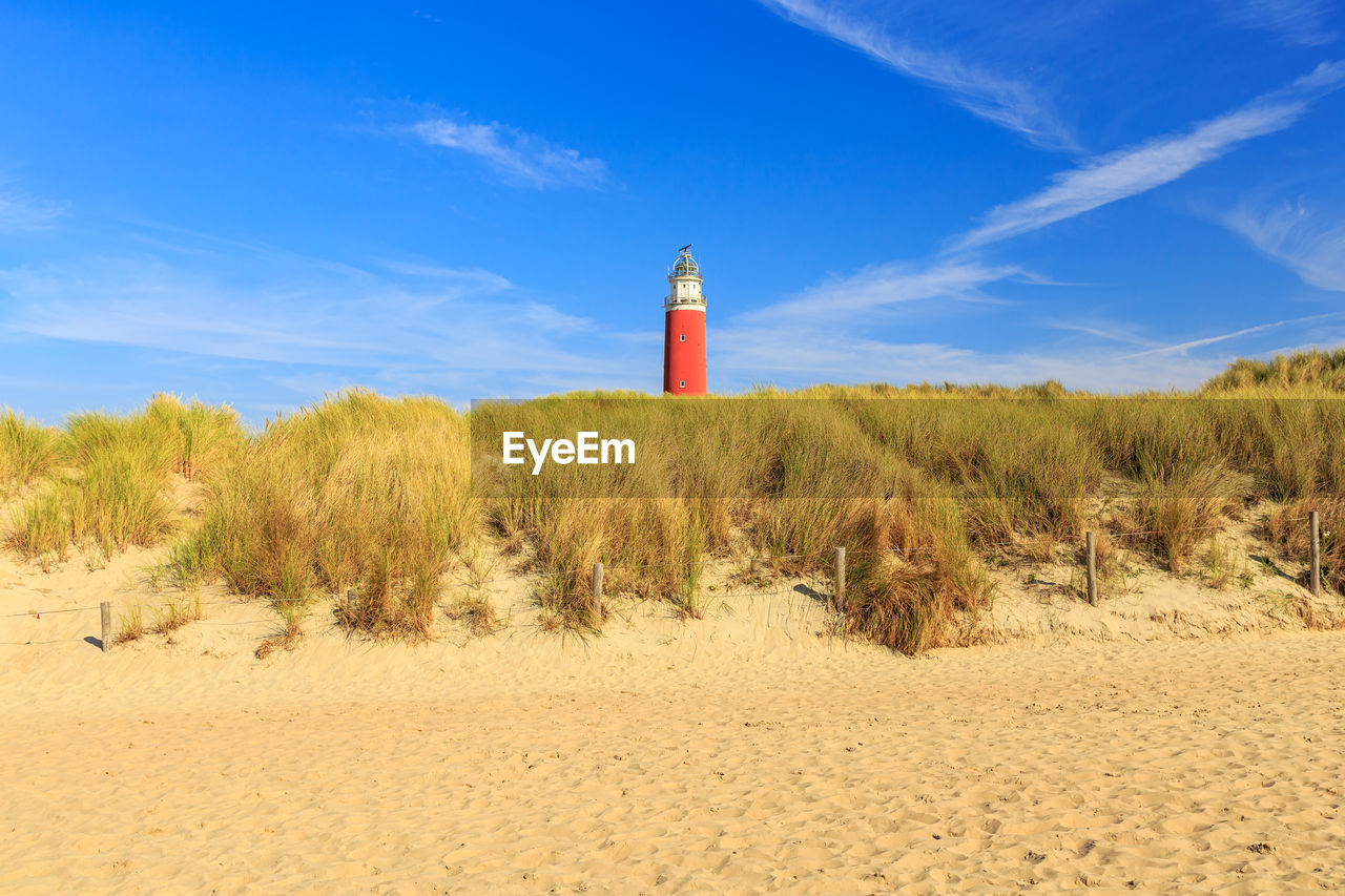 Lighthouse by beach against sky