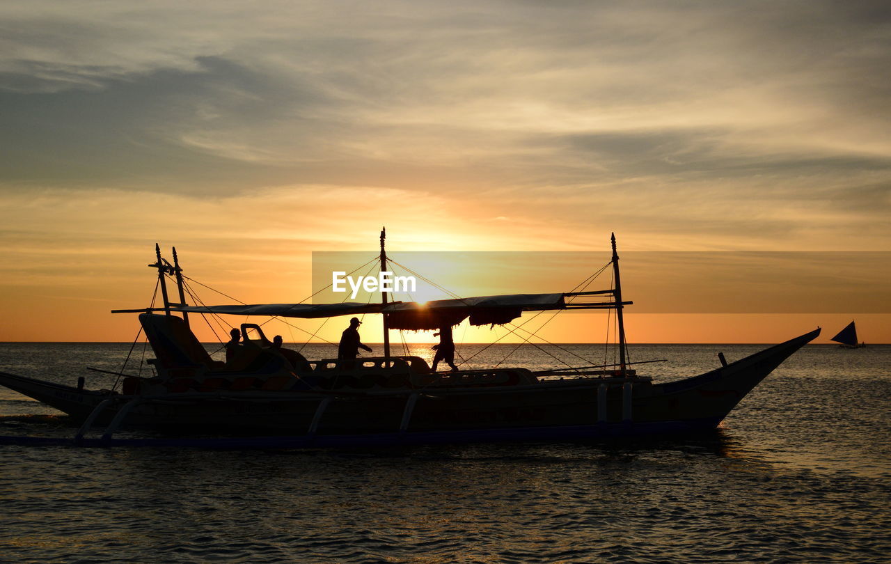 SILHOUETTE SAILBOATS IN SEA AGAINST ORANGE SKY