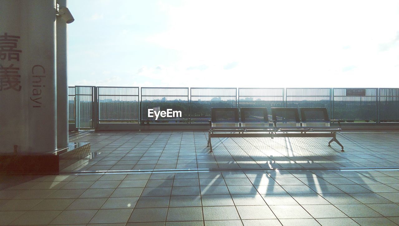 Empty seats outside station against sky