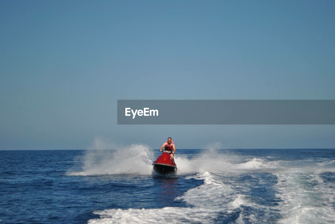 Man jet boating on sea against clear blue sky