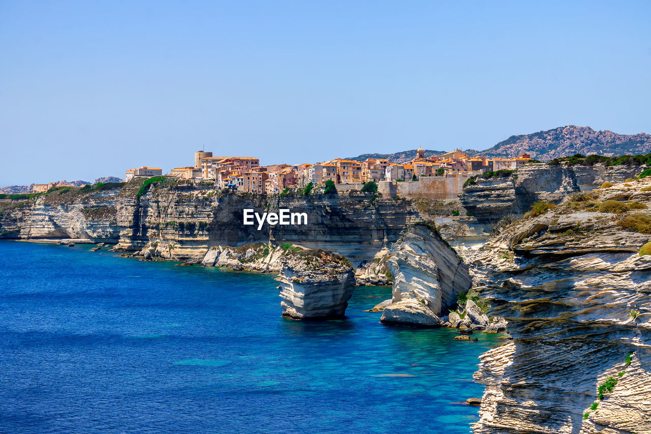 Panoramic shot of cityscape by sea against clear blue sky