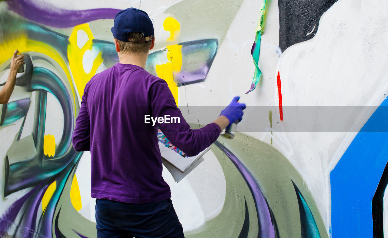 Rear view of man painting on wall