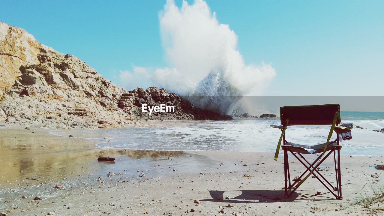 Waves splashing on rocks against sky at beach