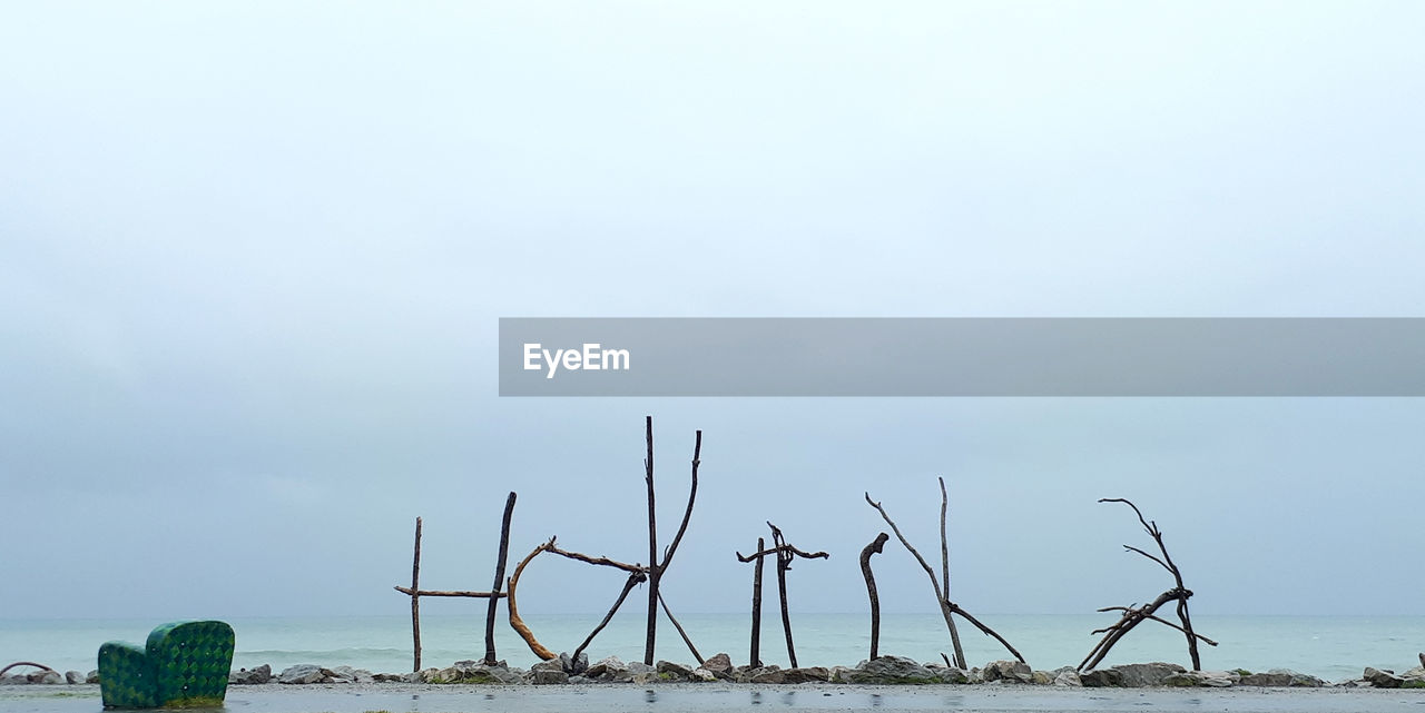 Text made from sticks at beach against sky