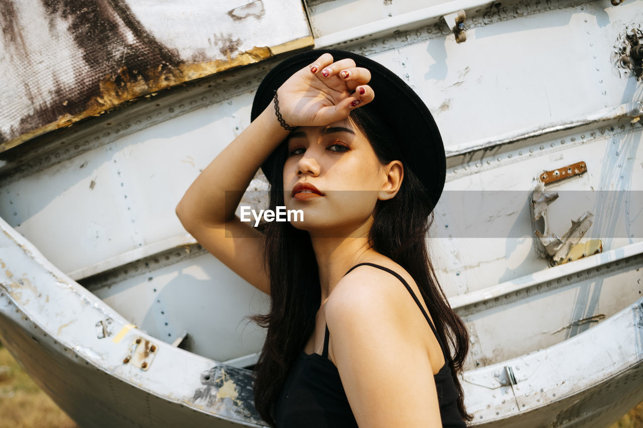 Portrait of woman looking away while standing against wall