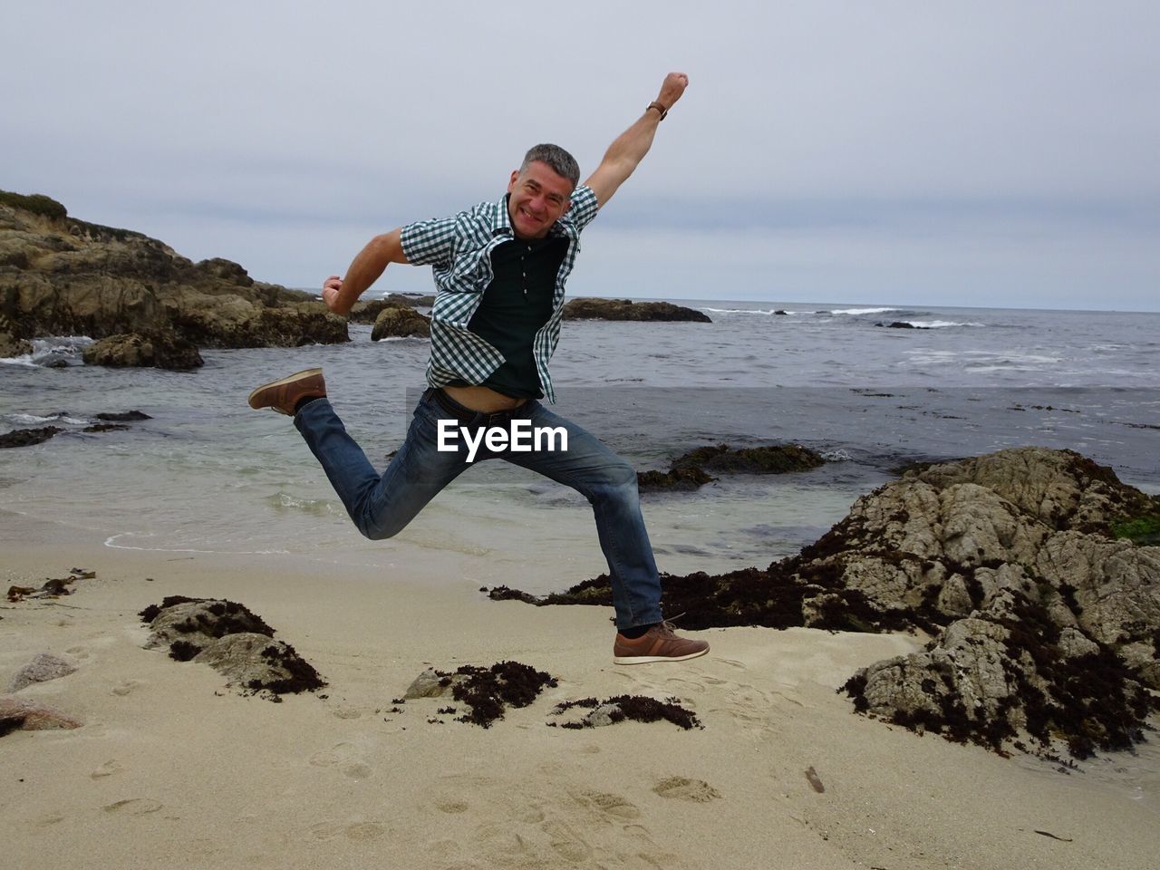 Full length of man jumping at beach against sky