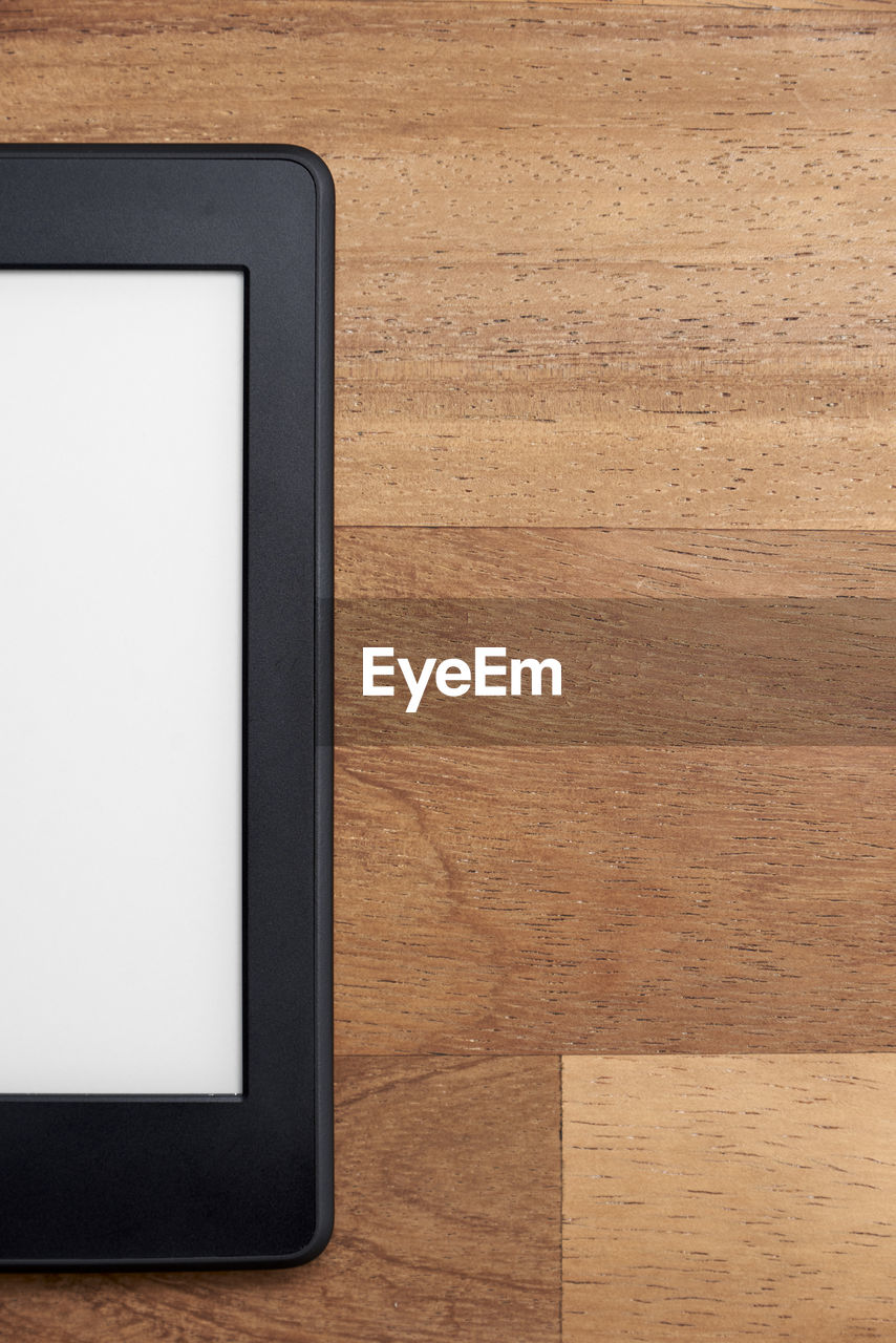 Closeup, electronic reader with blank screen, wood surface. concepts of technology and modernity.
