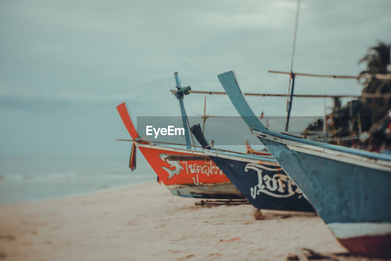 BOAT MOORED ON SHORE AGAINST SKY