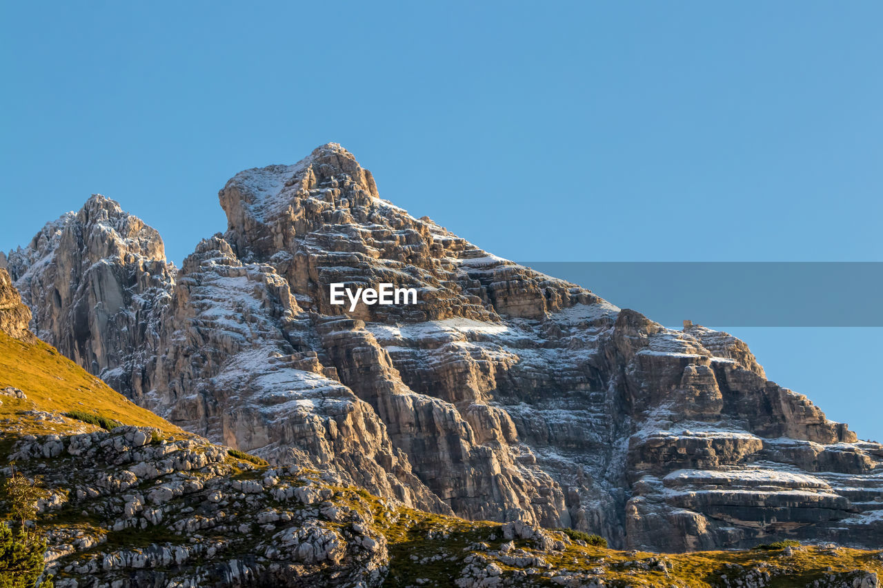 Low angle view of rock formation against clear blue sky