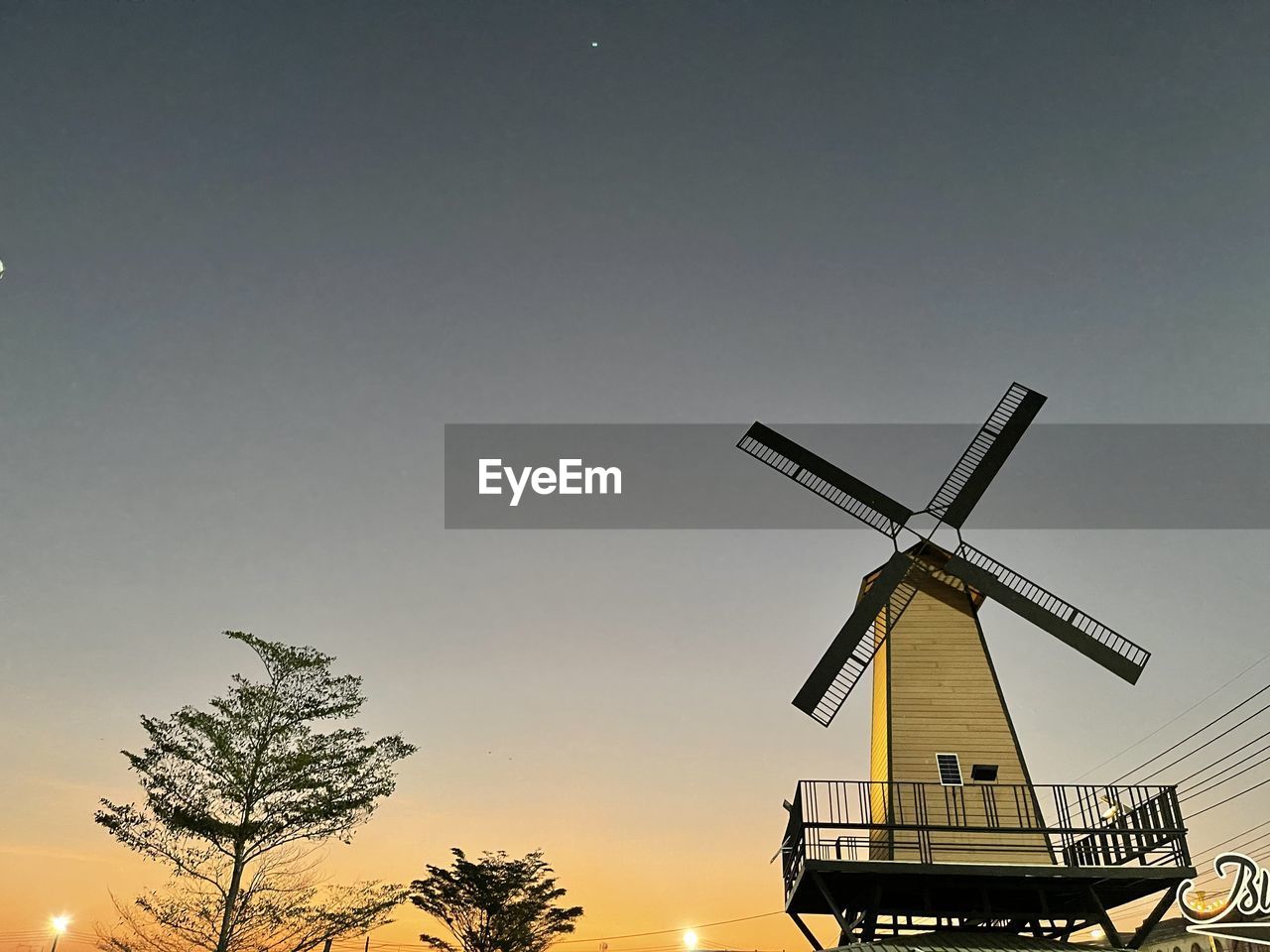 LOW ANGLE VIEW OF TRADITIONAL WINDMILL AGAINST SKY DURING SUNSET