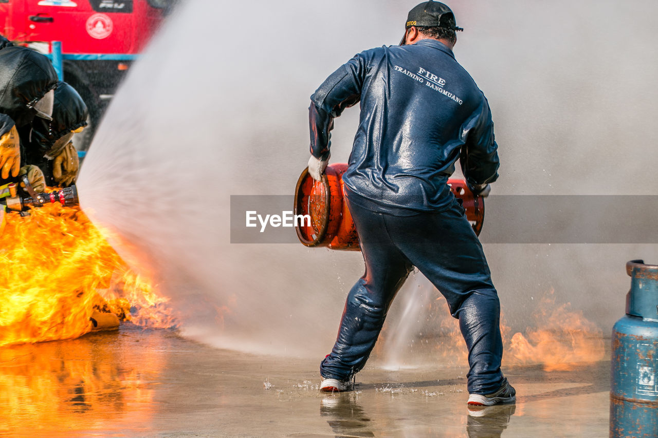 Rear view of firefighter holding cylinder