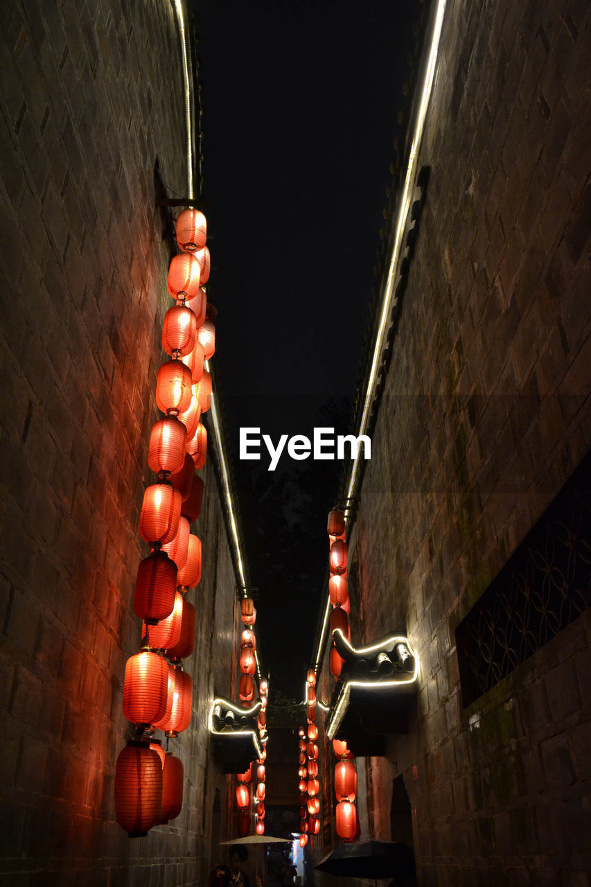 LOW ANGLE VIEW OF ILLUMINATED LANTERNS HANGING BY WALL